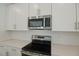 Close up of the modern range top and microwave in the spacious and clean, white kitchen at 4075 Bannock Ave, Tavares, FL 32778