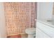 Close up on a toilet next to a sink and patterned shower curtain in this bright bathroom at 5140 Four Strand Ct, St Cloud, FL 34772