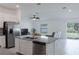 Open kitchen flows into the living area, featuring stainless steel appliances, white cabinets, and tile floors at 5140 Four Strand Ct, St Cloud, FL 34772