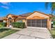 Charming single-story home featuring a screened two-car garage and lush landscaping under a sunny blue sky at 6017 Hickory Grove Ln, Port Orange, FL 32128