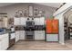 A well-equipped kitchen with stainless steel appliances, white cabinets, and a striking orange refrigerator at 6017 Hickory Grove Ln, Port Orange, FL 32128