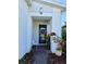 The front door of a white house features a decorative wreath, plants, and a white bench at 6608 Harper Way, Harmony, FL 34773