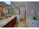 Elegant bathroom with double sinks, granite counters, a soaking tub, and a walk-in shower at 7664 Wilmington Loop, Kissimmee, FL 34747