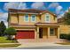 Charming two-story home features a red tile roof, red garage door, and meticulously maintained landscaping at 7664 Wilmington Loop, Kissimmee, FL 34747