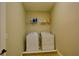 A compact laundry room with a washer, a dryer, and open shelving above at 7664 Wilmington Loop, Kissimmee, FL 34747