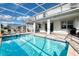 Beautiful screened-in pool area with sun loungers, patio furniture, and a built-in spa at 9036 Stinger E Dr, Davenport, FL 33896