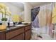 Bathroom with decorative shower curtain, granite countertop, and elegant floral arrangement at 9535 Silver Buttonwood St, Orlando, FL 32832