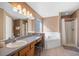 Bright bathroom featuring dual sinks, a soaking tub, and a glass-enclosed shower at 1048 Lake Berkley Dr, Kissimmee, FL 34746