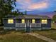Charming single-story home with a cozy front porch and lush green lawn at dusk at 1226 Pine St, Orlando, FL 32824