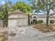 Charming single-story home featuring a two-car garage, arched window, and manicured landscaping at 1345 Tindaro Dr, Apopka, FL 32703