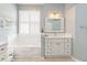 Light and airy bathroom featuring a soaking tub, white vanity, and a bright window with shutters at 1923 Lazy Oaks Loop, St Cloud, FL 34771