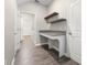 A bright office nook with a built-in desk, floating shelves, and tile flooring near a laundry room at 2017 Camden Loop, Davenport, FL 33837
