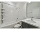 Bright bathroom featuring a shower-tub combination, white tile, gray vanity, and a large mirror at 2238 Gold Dust Dr, Clermont, FL 34715