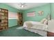 A bedroom with green walls and carpet, featuring a bed, bookshelf and a ceiling fan at 224 Pennsylvania Ave, St Cloud, FL 34769