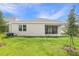 Spacious backyard with green grass, young trees and a view of the home's rear facade at 306 Alexandrite St, Deland, FL 32720