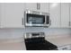 Modern kitchen featuring stainless steel microwave and black electric range with white cabinets at 306 Alexandrite St, Deland, FL 32720