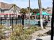 Community pool area featuring mature landscaping, outdoor seating, and a black metal fence at 3100 Parkway Blvd # 113, Kissimmee, FL 34747