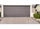 Close-up of a brown two-car garage door with decorative panels and a brick paver driveway at 333 Almansa St, Davenport, FL 33837