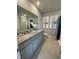 Bathroom features granite countertops, double sinks, soft gray cabinetry, and decorative art at 4247 Shackelford Ct, Orlando, FL 32824