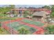 View of the community tennis courts with red and green surface, set among lush landscaping and residential buildings at 5316 Burning Tree Dr # A09-2, Orlando, FL 32811