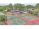 View of the community tennis courts with green and red surface and well-maintained fencing, surrounded by trees and landscaping at 5316 Burning Tree Dr # A09-2, Orlando, FL 32811