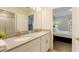 Bright bathroom features dual sinks with light countertops and mirrors with an additional bedroom in view at 581 Pebble Beach Dr, Davenport, FL 33896