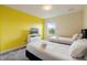 This bedroom features two twin beds, yellow accent wall, and a window overlooking the property at 581 Pebble Beach Dr, Davenport, FL 33896