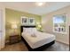 This bedroom features a queen bed, green accent wall, lamps, and a view through the window at 581 Pebble Beach Dr, Davenport, FL 33896