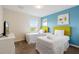 Bedroom features twin beds, blue accent wall, wall art and exterior view through the window at 581 Pebble Beach Dr, Davenport, FL 33896