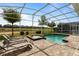 Screened-in pool and spa area with lounge chairs overlooking a well-maintained lawn and putting green at 581 Pebble Beach Dr, Davenport, FL 33896