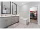 Modern bathroom with double vanities, a tub, and a walk-in closet accessible through a doorway at 7629 Marietta St, Orlando, FL 32807