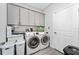 Well-lit laundry room with front-load washer and dryer, gray cabinets, and wood-look tile floors at 7629 Marietta St, Orlando, FL 32807