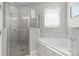 Bathroom featuring a glass-enclosed shower, soaking tub, and marble tile at 7665 Fairfax Dr, Kissimmee, FL 34747