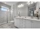 Bathroom with double sink vanity, a large mirror, and shower with marble tile at 7665 Fairfax Dr, Kissimmee, FL 34747