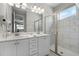 Bathroom featuring double sink vanity and a marble tiled shower with glass door at 7665 Fairfax Dr, Kissimmee, FL 34747