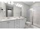 A bathroom featuring double sinks, walk-in shower, and white cabinetry at 7665 Fairfax Dr, Kissimmee, FL 34747