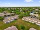 A neighborhood aerial view with green lawns, trees, beige buildings, parking and a pond in the distance at 1225 Coral Coast Dr, Orlando, FL 32824