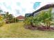 Green backyard featuring tropical landscaping, a well-manicured lawn, and a view of the screened-in lanai at 3704 Via Monte Napoleone Dr, Poinciana, FL 34759