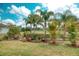 Landscaped lawn featuring mature palm trees, vibrant flowers, and manicured shrubs at 3704 Via Monte Napoleone Dr, Poinciana, FL 34759