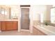 Bright bathroom with a glass door shower, soaking tub, and wood cabinetry with double sinks at 423 Corvina Dr, Davenport, FL 33897
