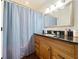 Bathroom showcasing a wood vanity with a dark countertop and a blue shower curtain at 1102 Solana Cir, Davenport, FL 33897