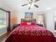 Bedroom featuring wood floors, dark furniture, a ceiling fan, and a bed with red patterned bedding at 1102 Solana Cir, Davenport, FL 33897