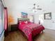 Cozy bedroom featuring a ceiling fan, wood floors, and a comfortable bed with red and white patterned bedding at 1102 Solana Cir, Davenport, FL 33897