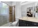 Bathroom with glass shower, dark vanity, and framed mirror reflecting the bedroom at 1821 N Hampton Dr, Davenport, FL 33897