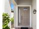 Close-up of a neutral colored front door with glass panels and white trim, next to manicured greenery at 1821 N Hampton Dr, Davenport, FL 33897