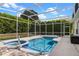 Screened-in pool and hot tub, surrounded by a tiled patio and lush landscaping at 1821 N Hampton Dr, Davenport, FL 33897