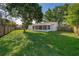 Lush backyard with a spacious lawn, mature trees, and a privacy fence creating a serene outdoor space at 201 La Paz Dr, Kissimmee, FL 34743