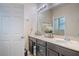 Well-lit bathroom featuring double sinks with dark cabinets, a large mirror, and a door leading to another room at 2820 Avian Loop, Kissimmee, FL 34741