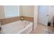 Bright bathroom featuring a white soaking tub with tile surround and a window with white blinds at 2820 Avian Loop, Kissimmee, FL 34741