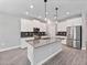 Modern kitchen with stainless steel appliances, white cabinetry, center island, and sleek countertops at 3038 Camden Way, Davenport, FL 33837